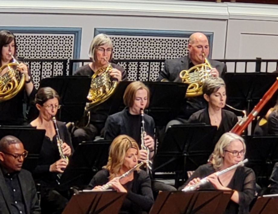 Close up of woodwind and horn section during a performance of the full orchestra dressed in their black outfits