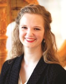 Carmel Symphony Orchestra's Principal Harp player, Melanie Mashner in black blazer seated in front of a ornately carved harp