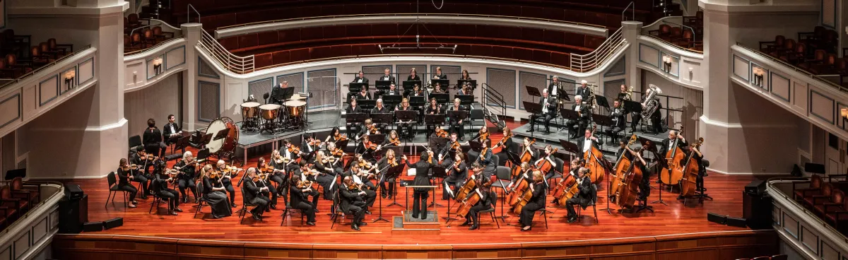Full orchestra on stage posed fora formal photo in Palladium before a concert