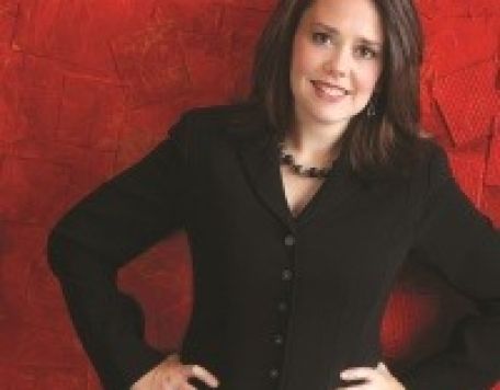 Carmel Symphony Orchestra Guest Conductor Kelly Corcoran in black suit with red  - Kelly Corcoran. Portrait by Bill Steber and Pat Casey Daley