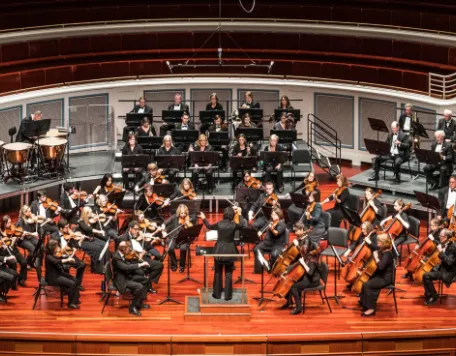 Full orchestra on stage posed fora formal photo in Palladium before a concert